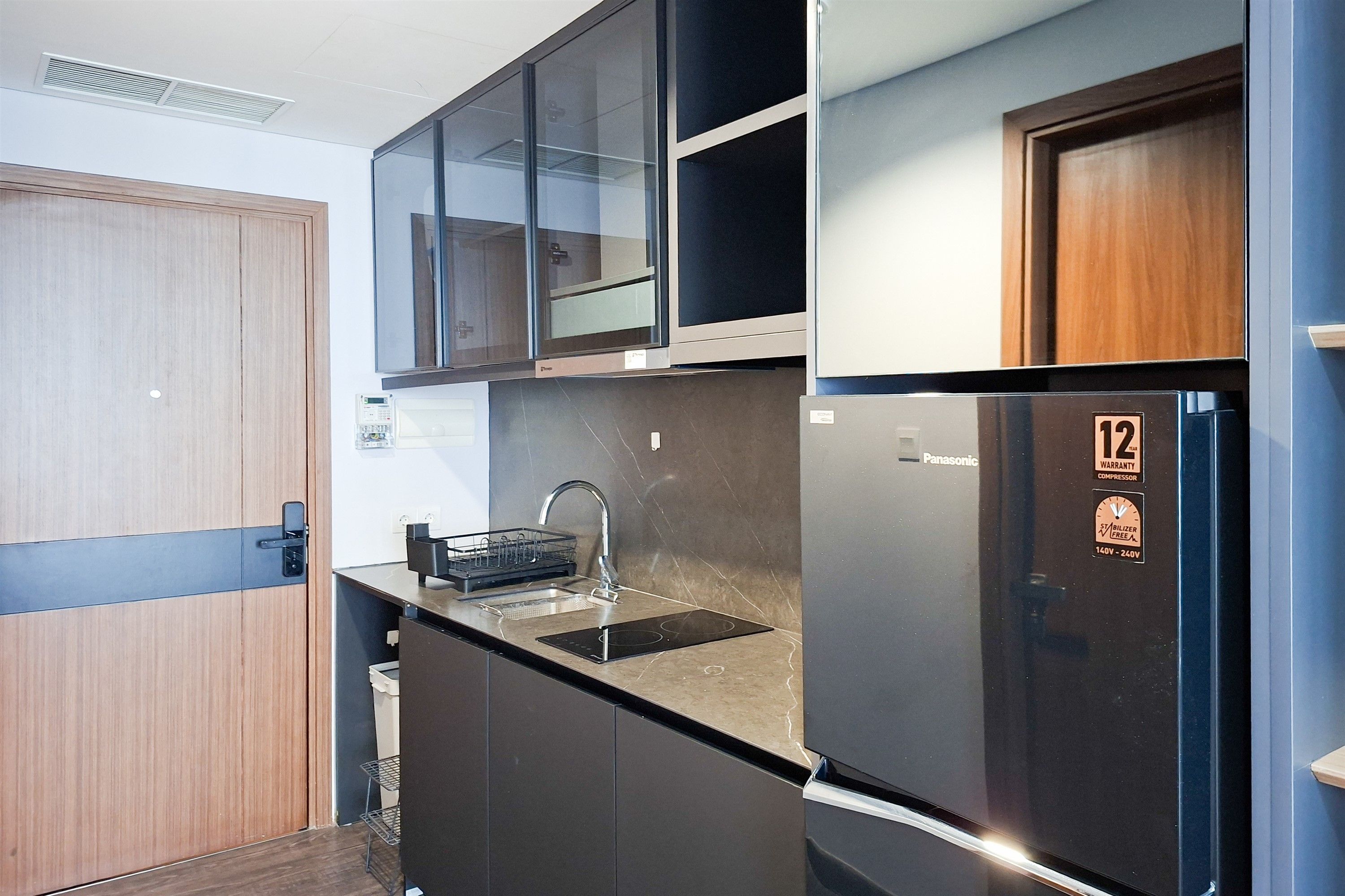 A compact kitchen with a built-in sink, a refrigerator, and a microwave.