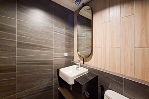 Een moderne badkamer met een rechthoekig wastafelmeubel, een spiegel en een toilet.