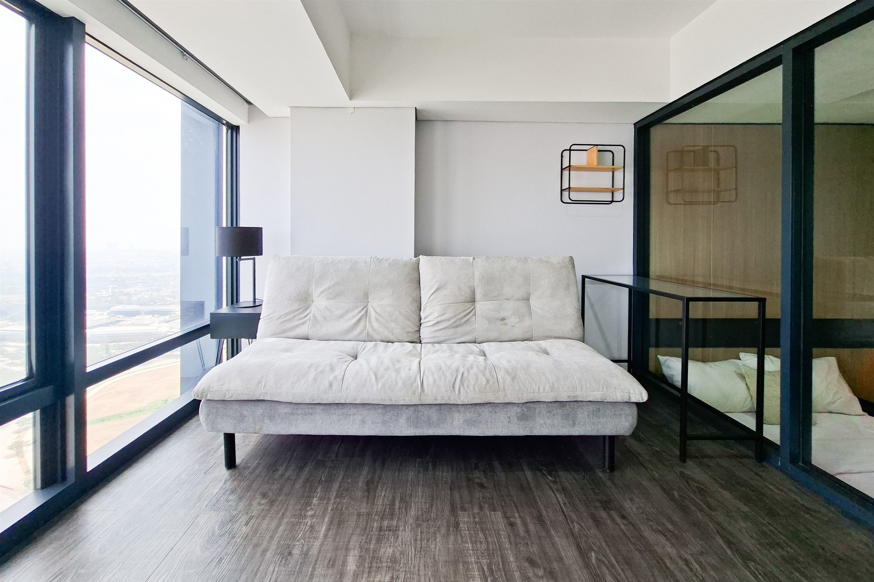 A modern bedroom with a large window, a bed, and a nightstand.