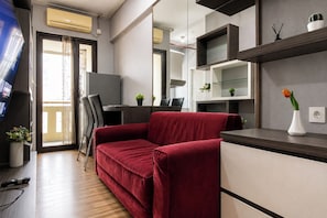 Ein modernes Wohnzimmer mit einem roten Sofa, einem Flachbildfernseher, einem Essbereich und integrierten Regalen.