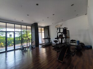 Ein geräumiger Fitnessraum mit unterschiedlichen Trainingsgeräten, großen Fenstern und Blick auf Grünflächen.