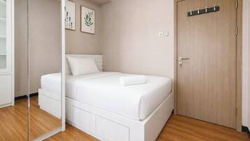 A bedroom with a bed, a wardrobe, a door, and a mirror.