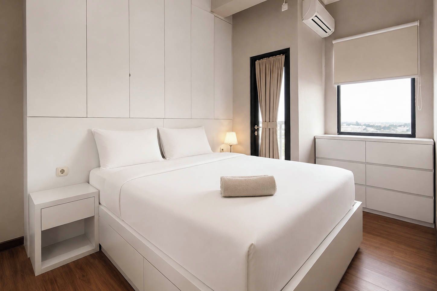 Una habitación de hotel moderna con una cama grande, mesitas de noche, un ventanal con vistas y espacio de almacenamiento integrado.