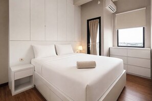 Una habitación de hotel moderna con una cama grande, mesitas de noche, un ventanal con vistas y espacio de almacenamiento integrado.