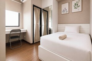 Ein Hotelzimmer mit Bett, Schreibtisch, Stuhl und Fenster.