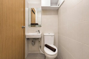 Un baño pequeño con un lavamanos blanco, un inodoro y un espejo sobre el lavamanos.
