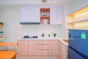 Eine moderne Küche mit weißen Schränken, einem eingebauten Backofen, einem Gasherd und einem Kühlschrank mit einem grünen Aufkleber.