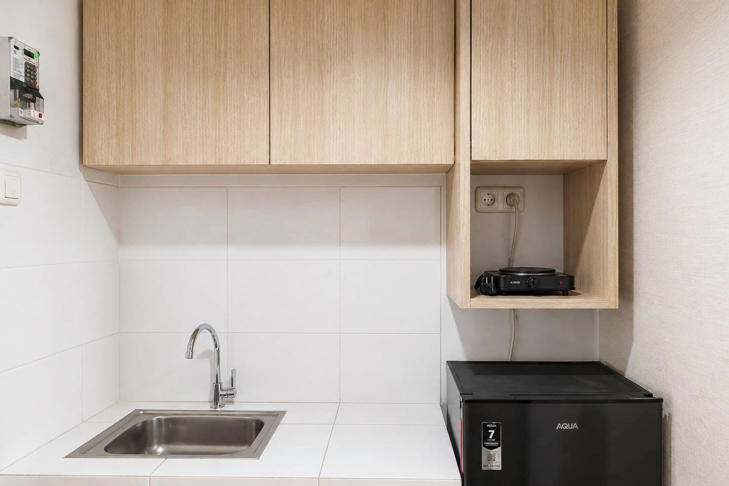 A kitchen with a stainless steel sink, wooden cabinets, and a black water dispenser.