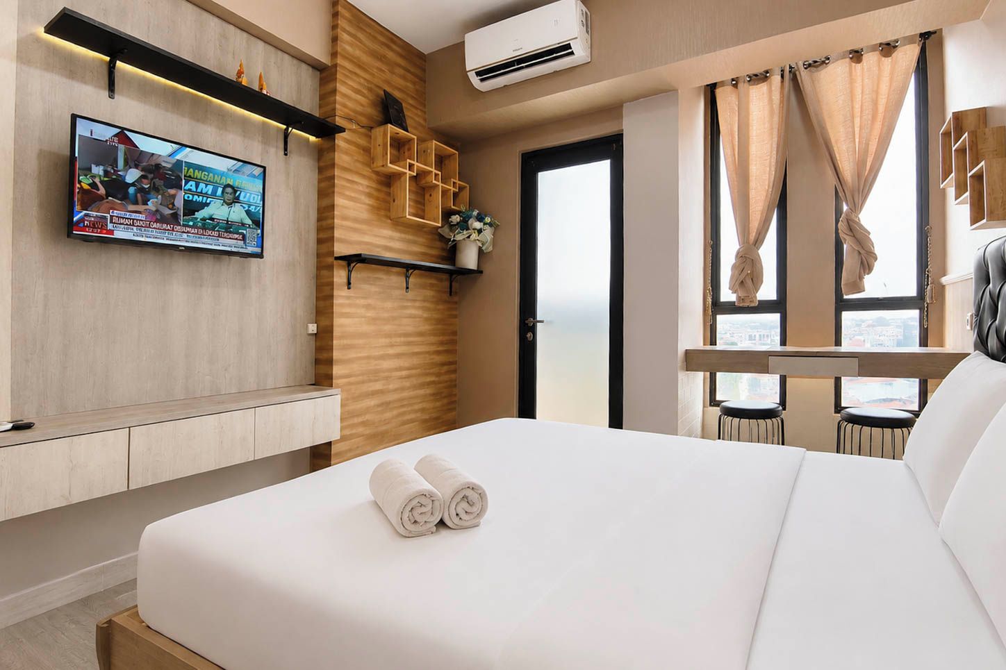 Quarto de hotel moderno com cama, TV fixada na parede e janela com cortinas.