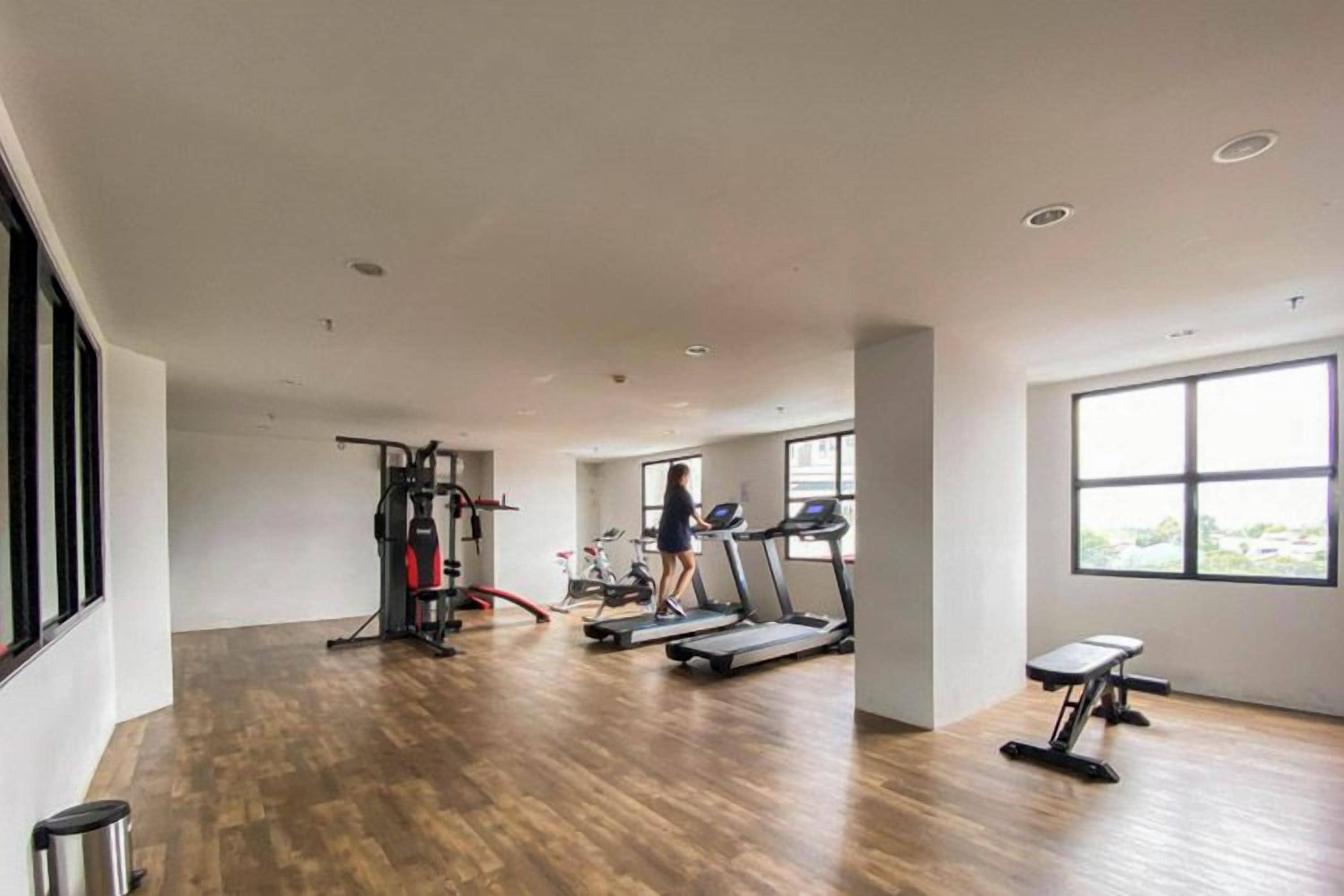 A spacious gym with cardio machines, a weight bench, and a treadmill.
