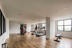 Ein geräumiger Fitnessraum mit Cardiogeräten, einer Hantelbank und einem Laufband.