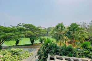 A park with a pond, trees, and a building in the background. - Cozy And Fully Furnished 1Br At Apartment Citralake Suites (Jakarta)