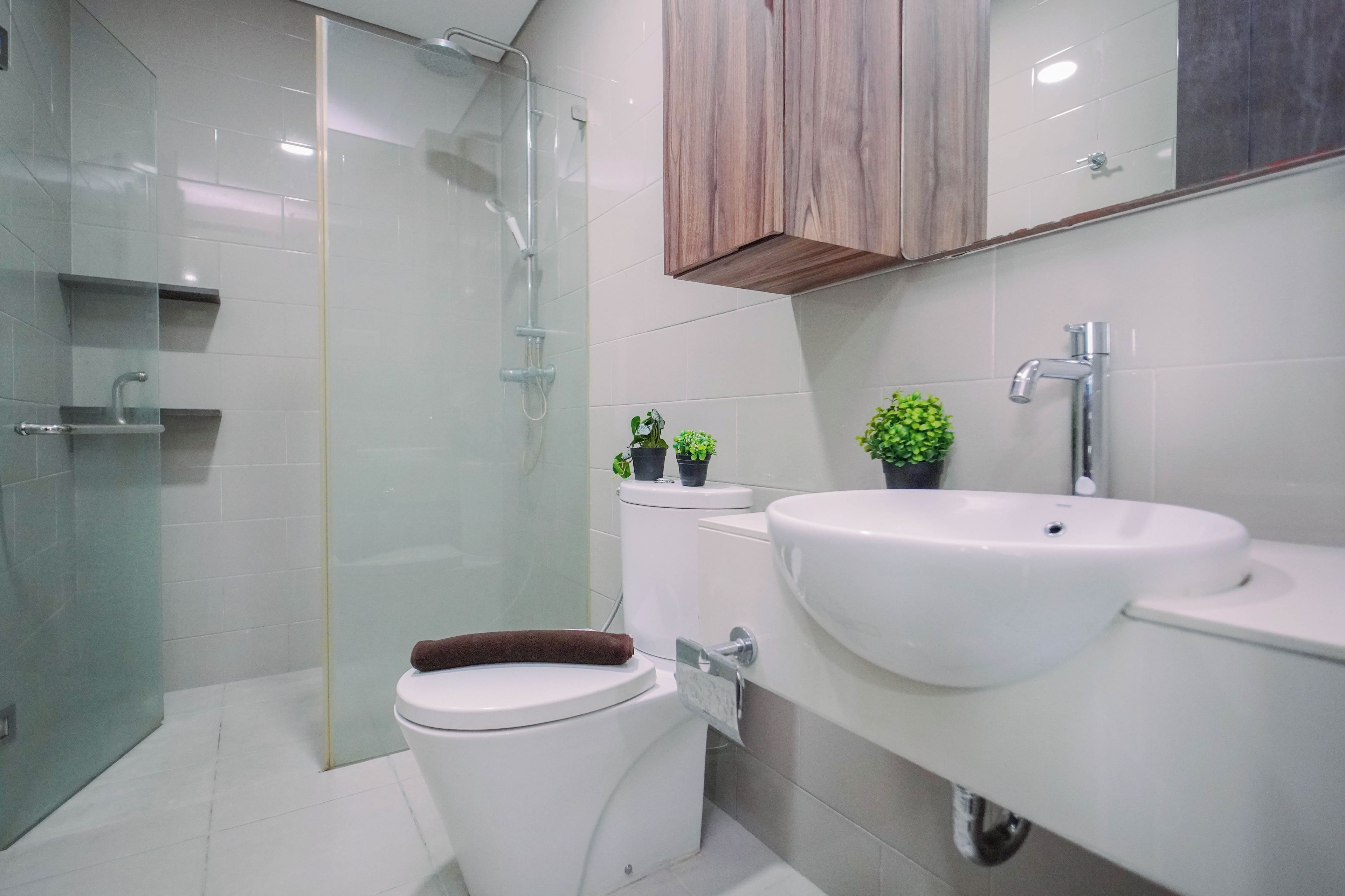 Une salle de bain moderne avec une douche à parois de verre, des toilettes, un lavabo et un meuble en bois placé au-dessus du miroir.
