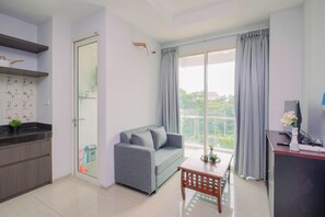 A modern apartment with a kitchenette, a grey sofa, a dining table, and a large sliding glass door to a balcony. - Cozy And Fully Furnished 1Br At Apartment Citralake Suites (Jakarta)