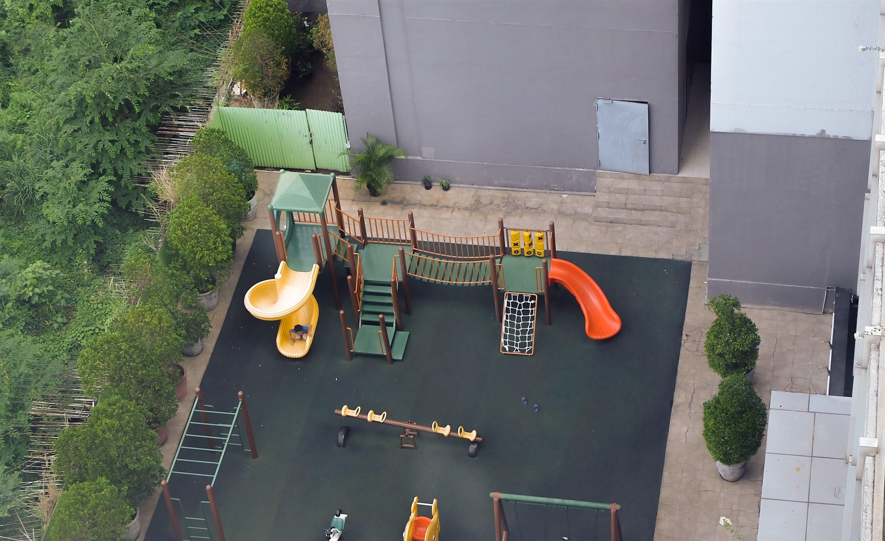 An aerial view of a playground with a slide, swings, and climbing structures.