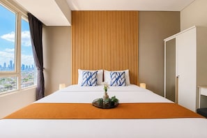 A hotel room with a large bed, a view of the city, and a window with curtains. - Homey And Roomy 3Br At Apartment Nifarro Park (Jakarta)