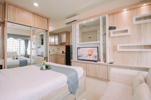 Ein Hotelzimmer mit Bett, Fernseher, einer Küchenzeile und einem Badezimmer.