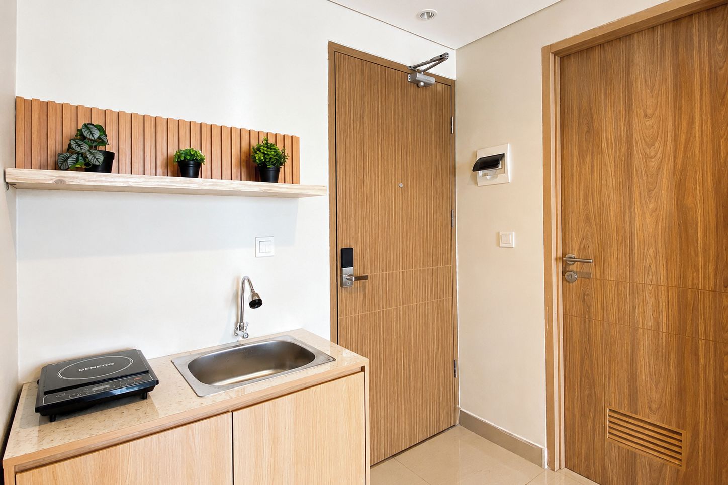 A compact kitchen with a sink, a built-in oven, and a wooden door.