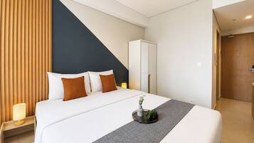 Una habitación de hotel con cama, mesita de noche, lámpara y una planta sobre la cama.