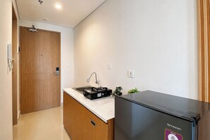 Eine kompakte Küche mit integriertem Kühlschrank, Spüle und kleiner Arbeitsfläche.