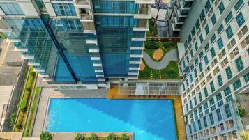 Un edificio alto con piscina y vegetación circundante.