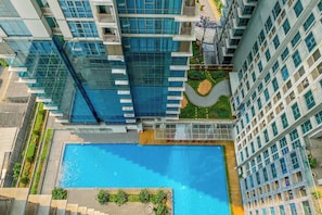 Um edifício alto com piscina e vegetação ao redor.