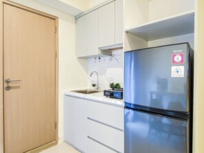 A kitchen with a stainless steel refrigerator, a sink, and white cabinets. - Strategic Location Studio Room At Apartment Meikarta District 2 (Cikarang)