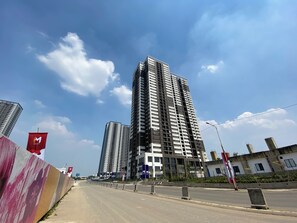 A high-rise building with a modern architectural design, featuring multiple floors and a prominent central tower. - Strategic Location Studio Room At Apartment Meikarta District 2 (Cikarang)