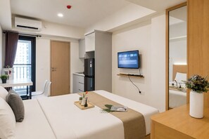 A hotel room with a bed, a desk, a television, and a wardrobe. - Strategic Location Studio Room At Apartment Meikarta District 2 (Cikarang)
