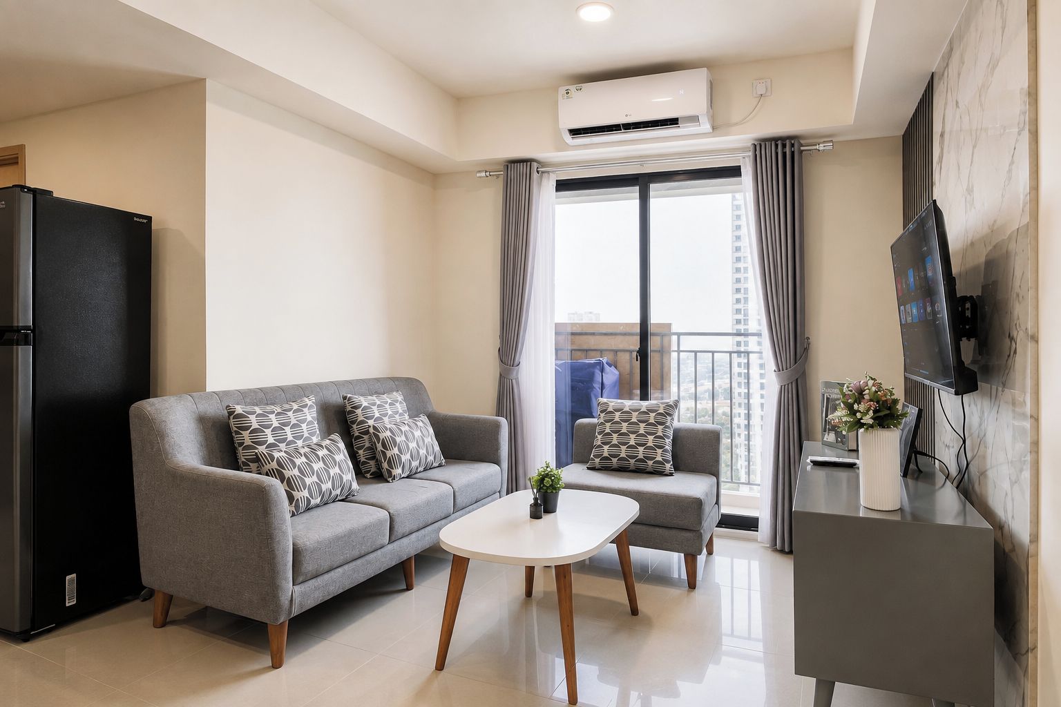 A modern living room with a grey sofa, a small coffee table, and a TV on the wall.