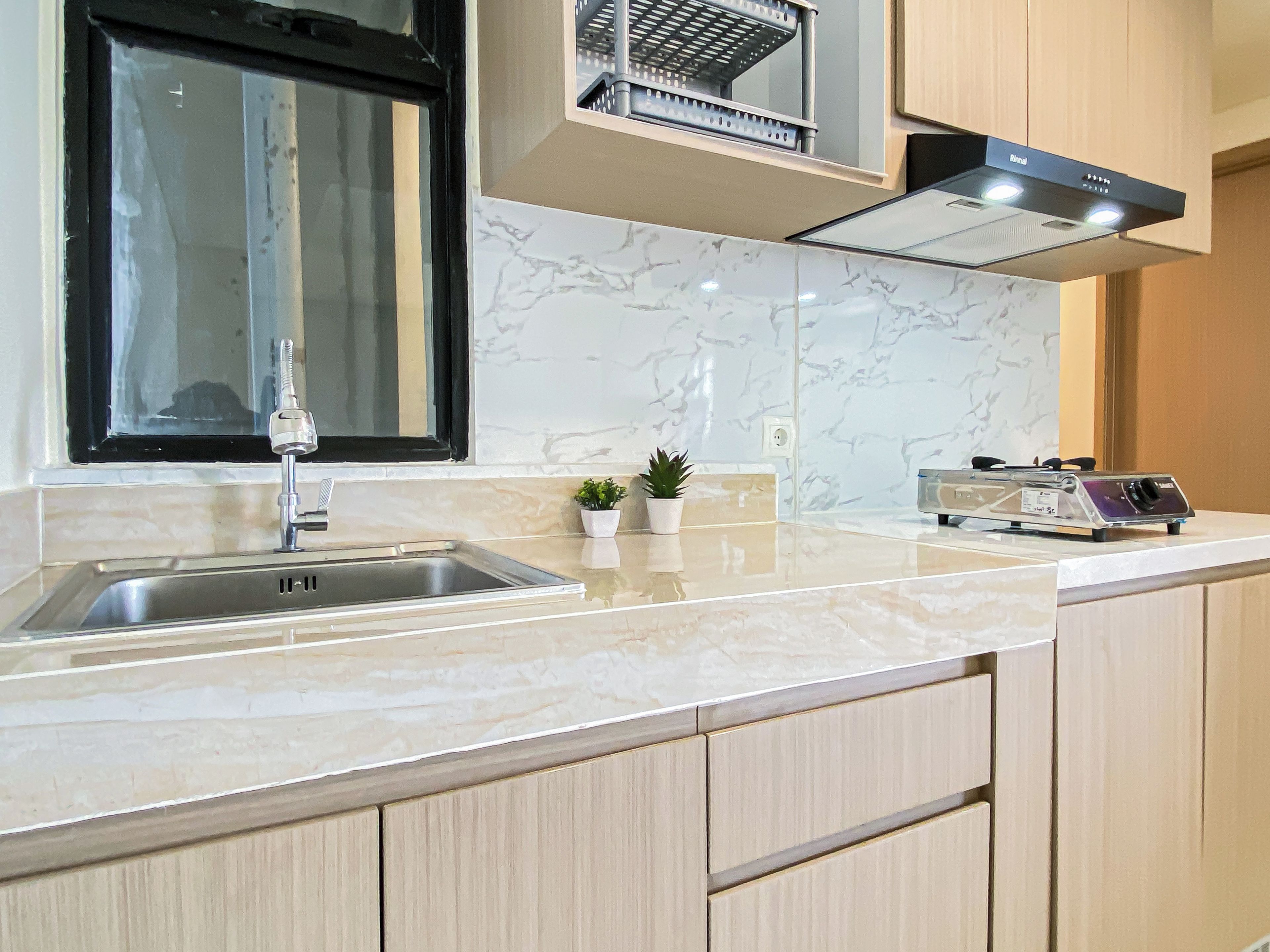 A kitchen with a stainless steel sink, a stove, and a window above the sink.