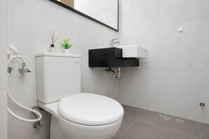 A modern bathroom with a toilet, a sink, and a mirror. - Modern And Homey Studio At Apartment Ciputra World 2 (Jakarta)