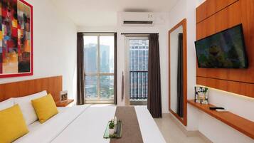 Una habitación de hotel con cama, televisión, ventana con cortinas y vista a la ciudad.