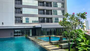Un hotel moderno con piscina, grandes ventanales y vistas del horizonte urbano.