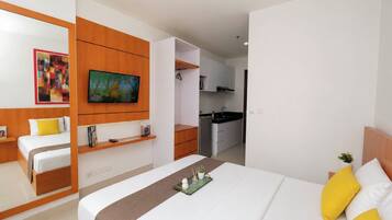 Habitación de hotel con cama, televisión, kitchenette y baño.