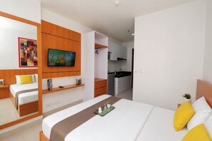 A hotel room with a bed, a TV, a kitchenette, and a bathroom. - Modern And Homey Studio At Apartment Ciputra World 2 (Jakarta)