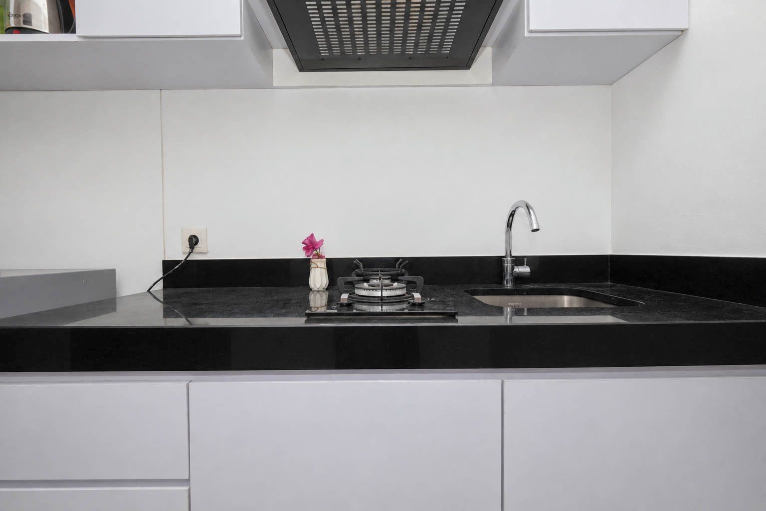 Una cocina moderna con encimera negra, pileta de acero inoxidable y estufa a gas.