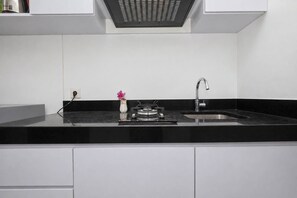 Une cuisine moderne dotée d’un plan de travail noir, d’un évier en acier inoxydable et d’une cuisinière à gaz.