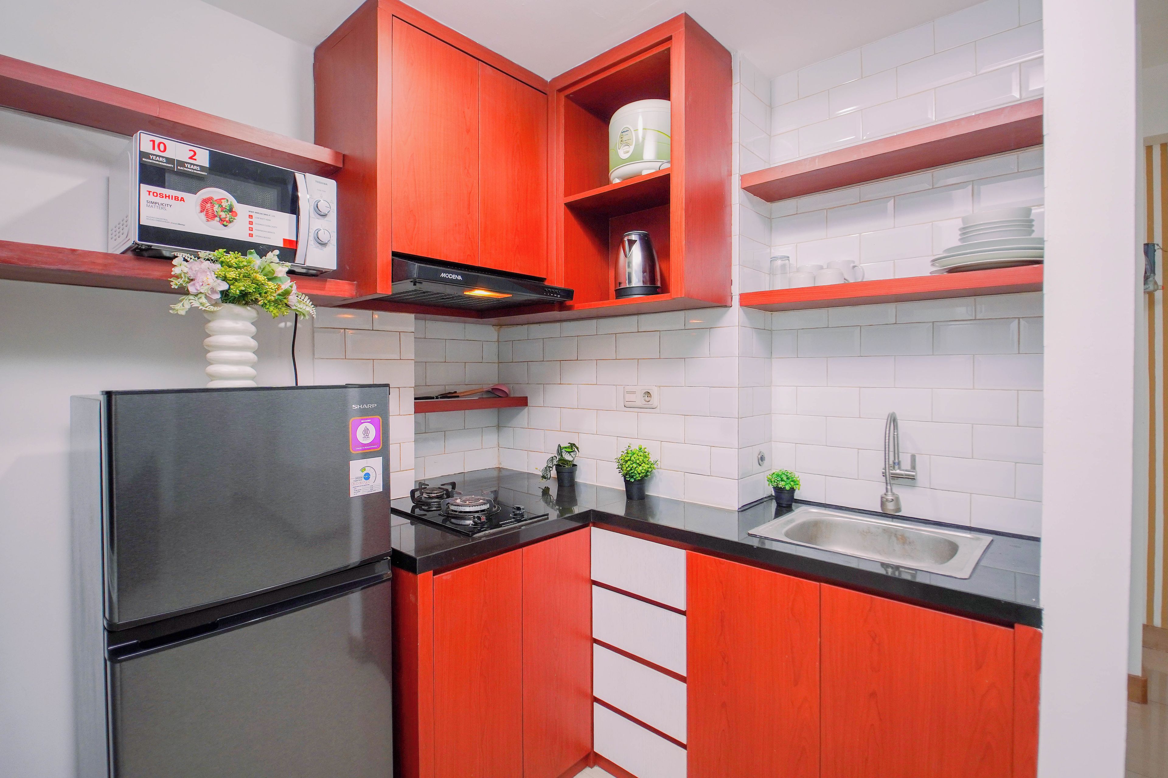 Cocina compacta con refrigerador, estufa y lavamanos.