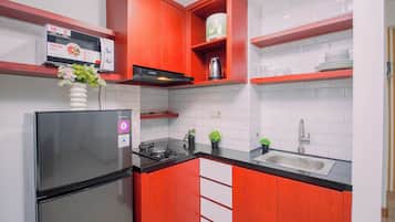 Cocina compacta con refrigerador, estufa y lavamanos.