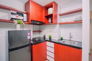 Cozinha compacta com geladeira, fogão e pia.