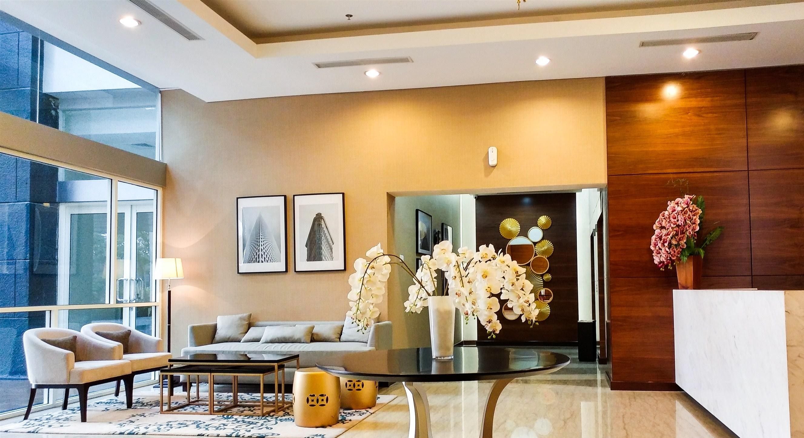 A modern hotel lobby with a sofa, chairs, a coffee table, and a reception desk.