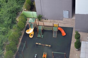Ein Spielplatz mit Rutsche, Kletternetz und Schaukeln.