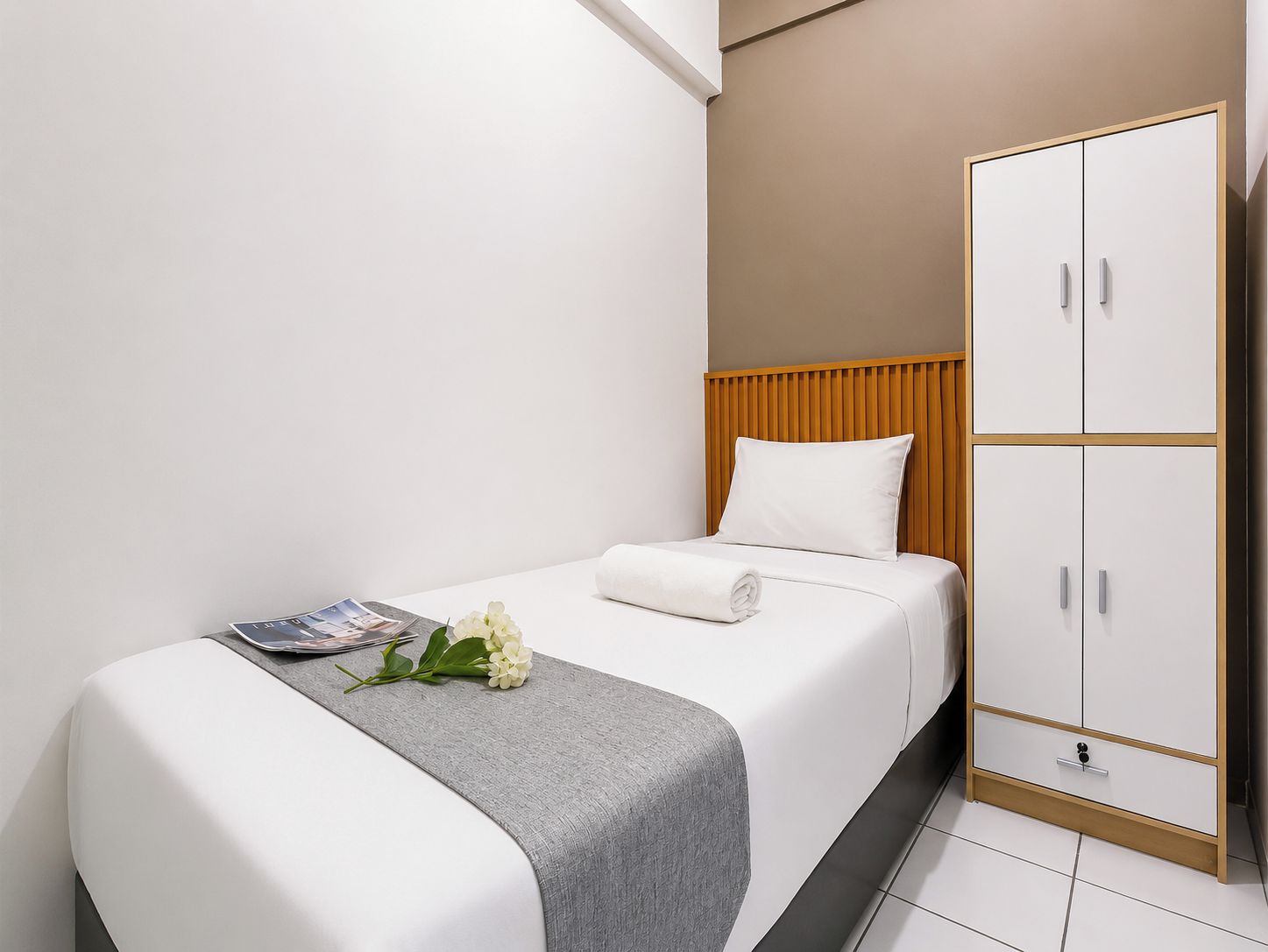 Habitación de hotel con cama, armario y una revista sobre la cama.