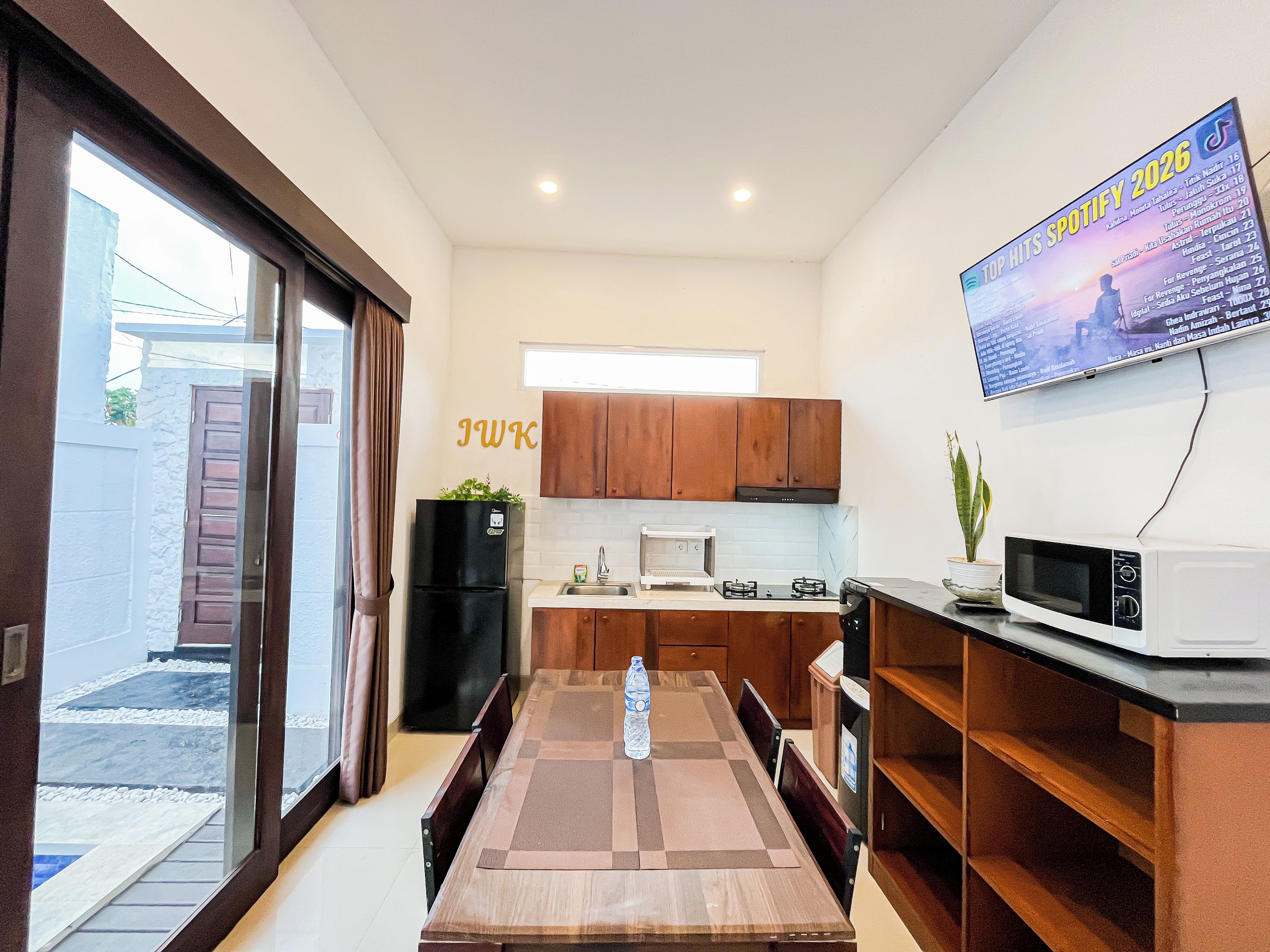Une cuisine compacte avec un coin repas, un téléviseur fixé au mur et un réfrigérateur.