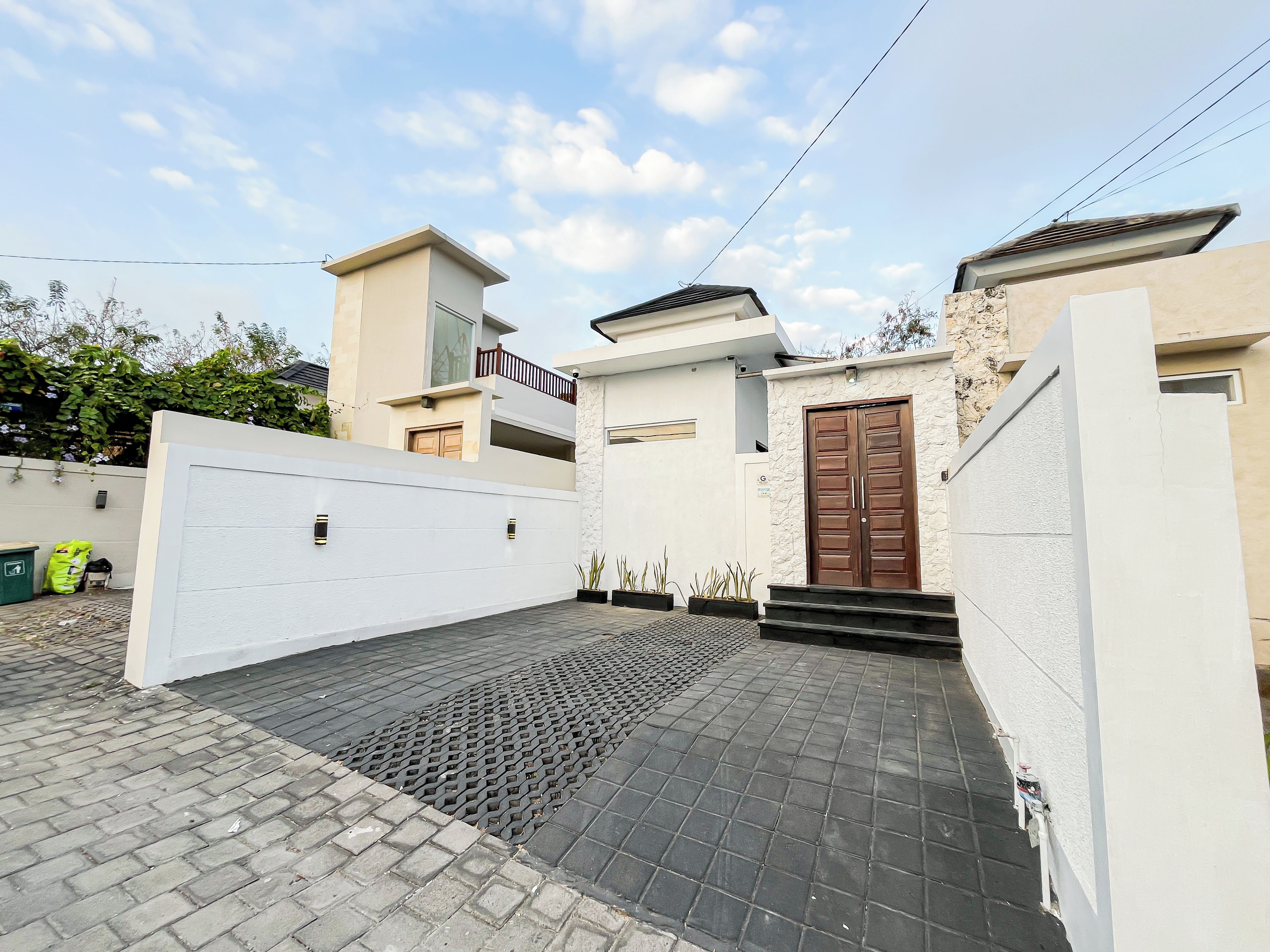 A modern two-story house with a gated driveway and a paved entrance.