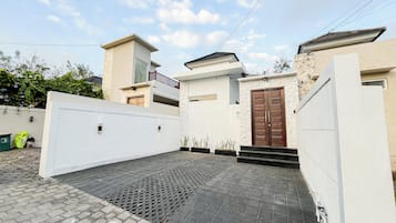 A modern two-story house with a gated driveway and a paved entrance.