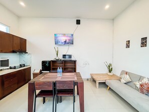 Eine moderne Küche mit Essbereich, einem flachbildfernseher an der Wand und einem Sofa mit Zierkissen.