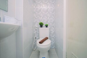 Ein Badezimmer mit Toilette, Dusche und Waschbecken. Auf der Toilette befinden sich zwei Blumentöpfe.