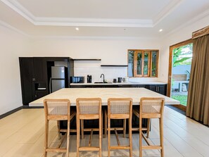 A modern kitchen with a large island, four bar stools, and a view of the outdoors. - 3Br Moriva Villa Ungasan Near Melasti Beach (Jimbaran)